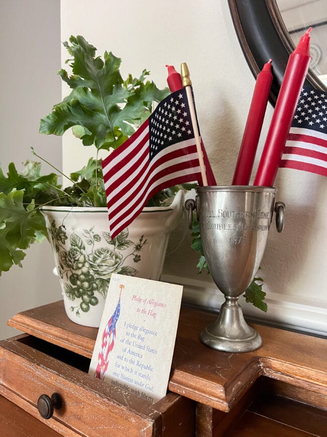 silver trophy cup with red candles and US flags and a plant in an old ice bucket