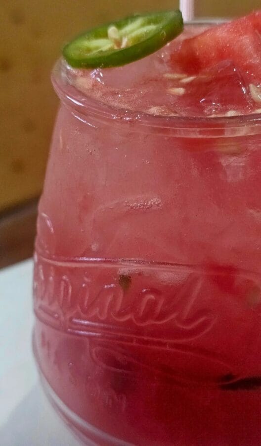 GLass of pink watermelon palona with a sliced jalapeno on top