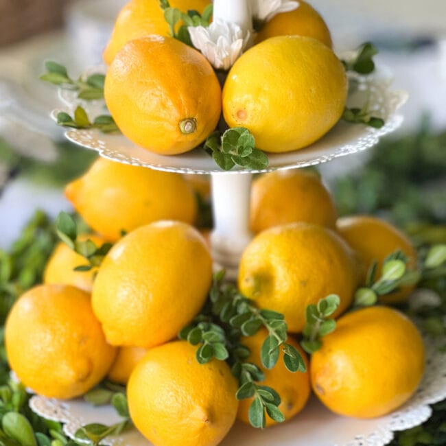 close up view of a two tiered tray with real lemons and boxwood stems poking out