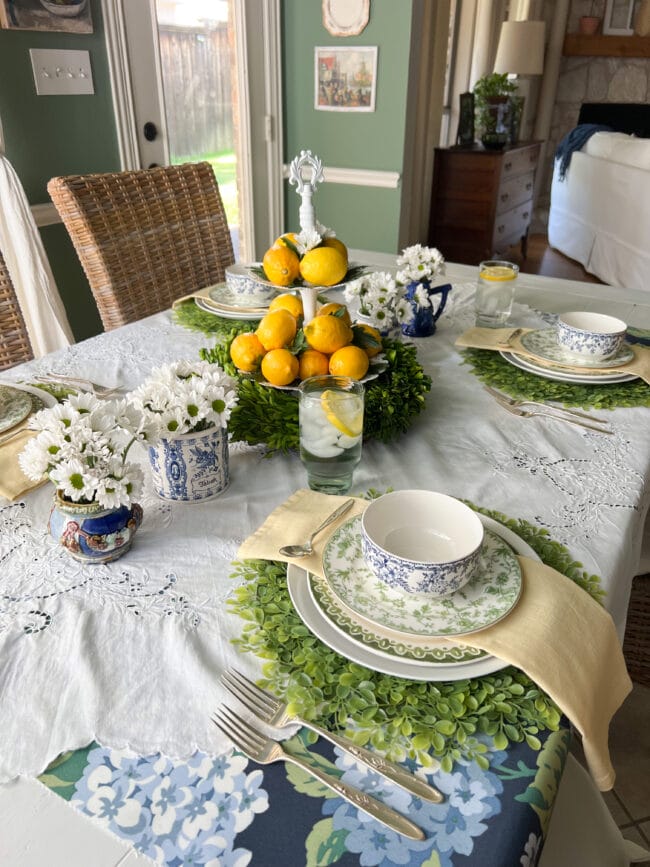 full table setting with lemon centerpiece, fresh white daisies and green and white plates