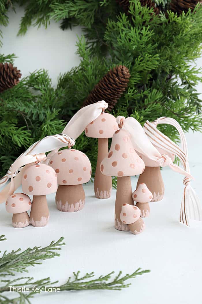 several pink and copper colored wood mushrooms turned into Christmas ornaments with matching ribbon