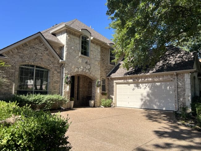 Stone house with beige trim and garage door