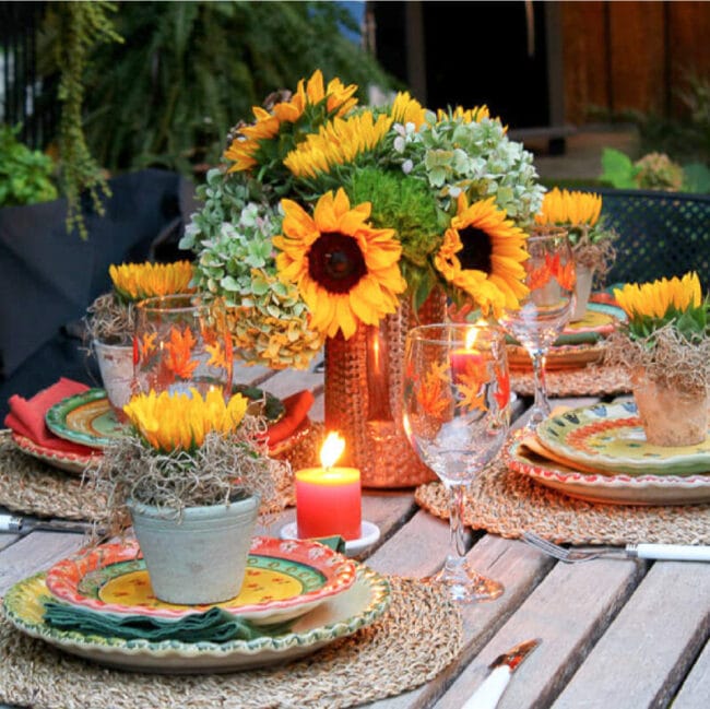 fall table setting with sunflowers, candles and plates