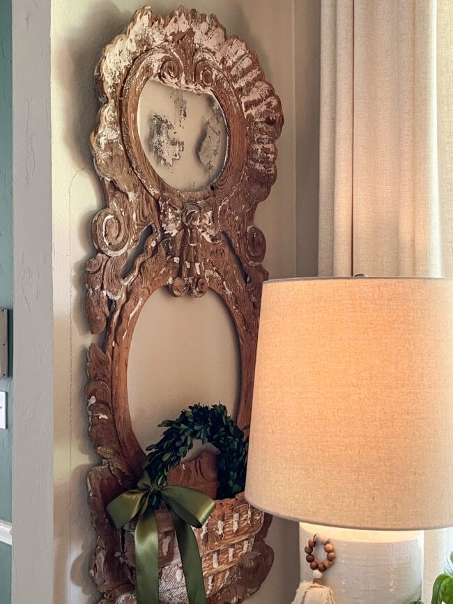 French antique mirror hanging on wall with a small boxwood wreath 