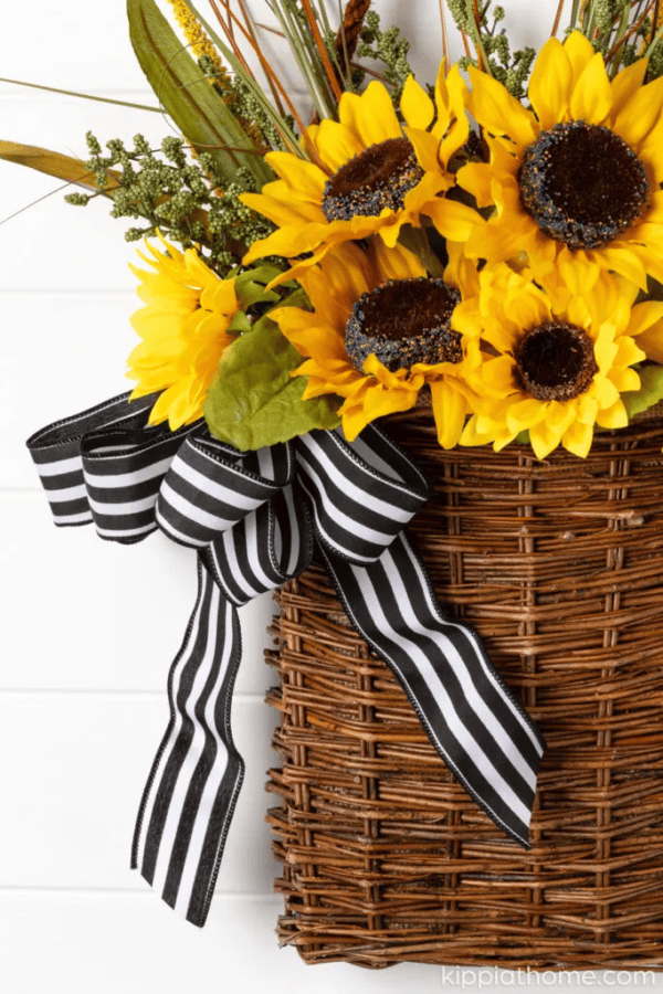 sunflowers in a hanging basket with black and white striped ribbon