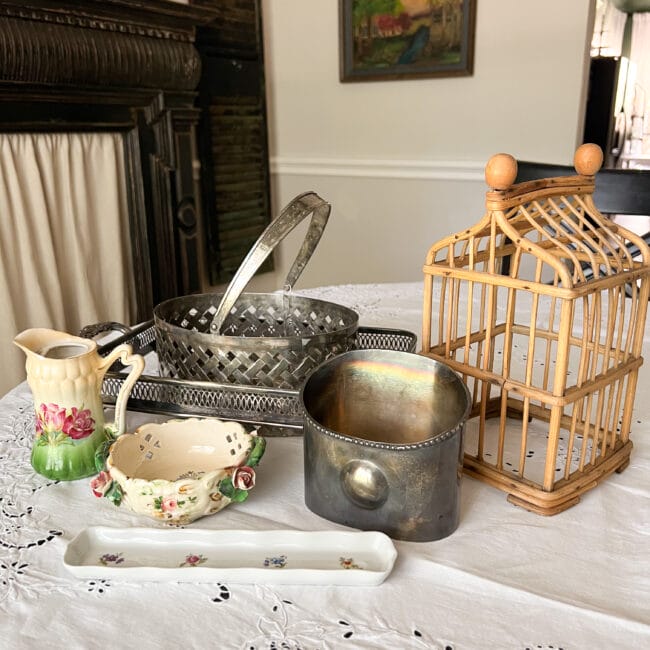 group of vintage finds: bamboo cage, silver basket, casserole dish, mail sorter, an olive holder and colorful dish and creamer