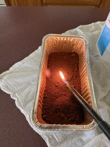 aluminum bread mold with coffee grounds and a lighter