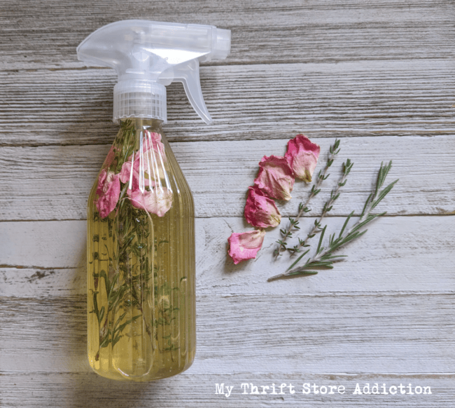 clear spray bottle with herbs and flowers inside