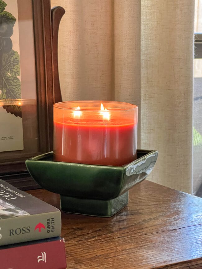 orange candle sitting inside a vintage green square shaped bowl