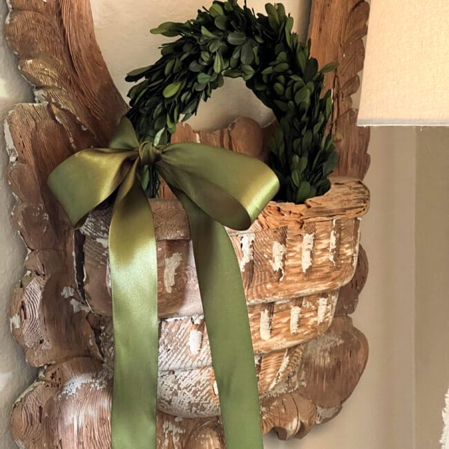 close up of antique French mirror with boxwood wreath and green ribbon