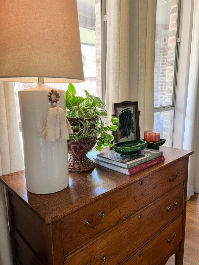 top view of an antique chest with a white lamp, plant, books and vintage green pottery