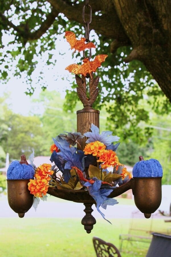 rusty chandelier hanging in tree with blue and orange halloween decor 