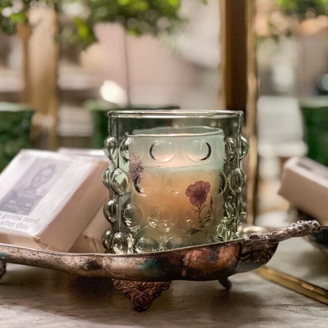 close up of a green bubble candle and soaps sitting on a silver plated tray