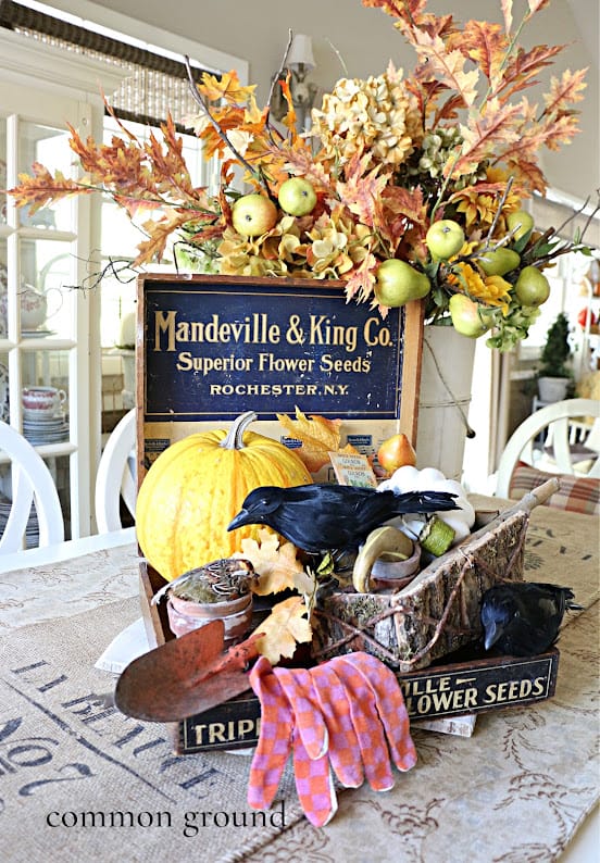 table centerpiece of halloween sign, large crow, pumpkins, fall stems and a sign