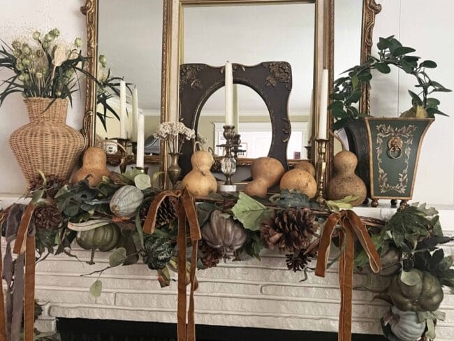 mantel with mirror, empty frames, candlesticks, garland and gourds