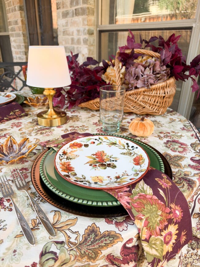 fall table with a colorful tablecloth, autumn dishes layered with fall napkins and lots of color
