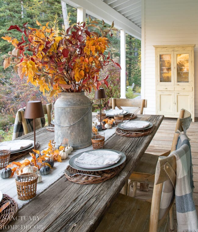 rustic fall table with a large can of fall leaves in the center of an outdoor table