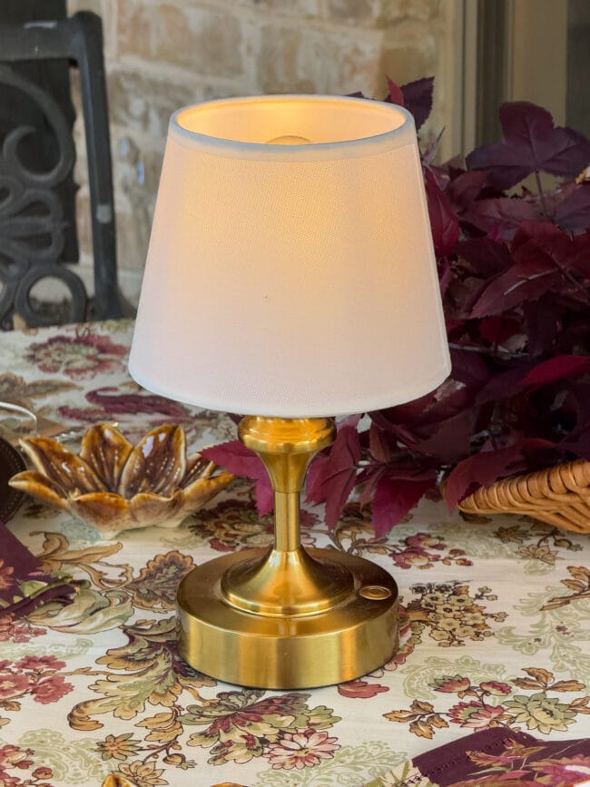 small rechargeable table lamp with a brass base and white shade