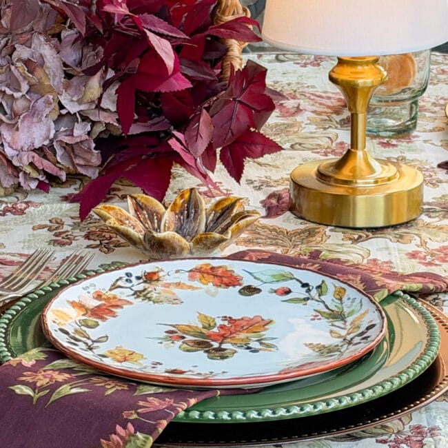 close up of autumn dishes, with faux leaves and small lamp in center of table