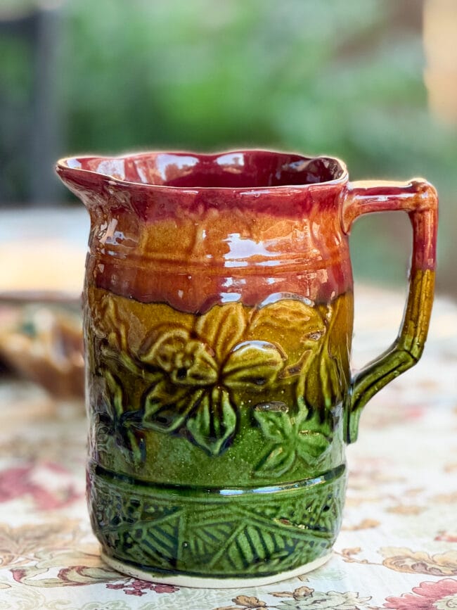 close up photo of a fall colored pitcher with green, gold and burgundy colors